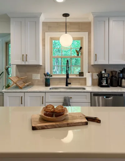 A kitchen with white cabinets and a window.