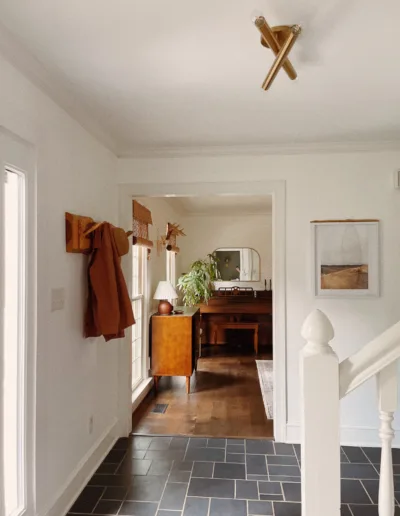 A hallway in a home with white walls and a wooden floor.