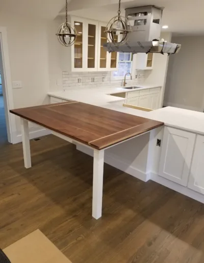 A kitchen with a wooden table in the middle.
