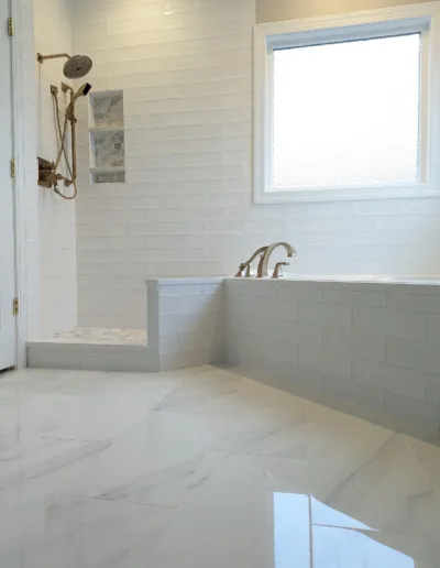 A white tiled bathroom with a tub and shower.