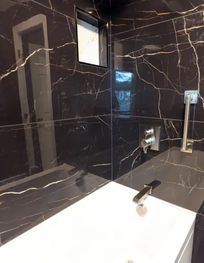 A bathroom with black marble walls and a bathtub.