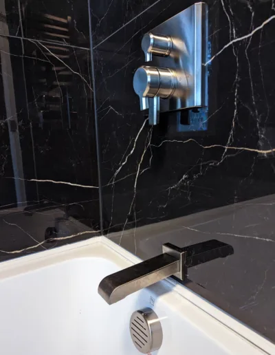 A bathroom with a black marble wall and faucet.