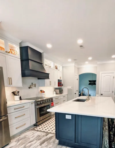 A white kitchen with a blue island and stainless steel appliances.