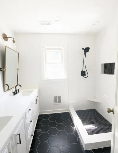 A white and black bathroom with a black tile floor.