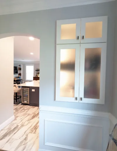 A kitchen with white cabinets and a glass door.