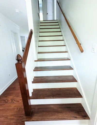 A stairway with wood treads and white walls.