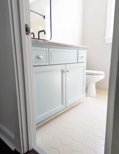 A bathroom with light blue cabinets and white tile.