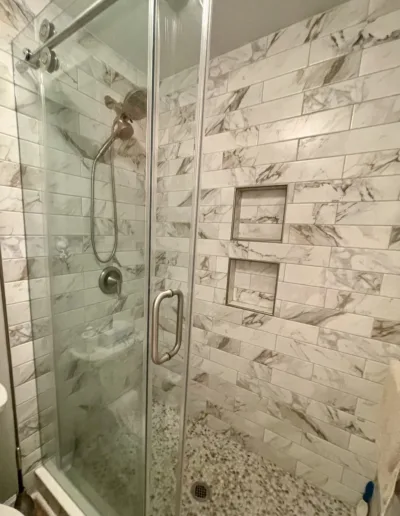 A bathroom with a glass shower stall and a toilet.